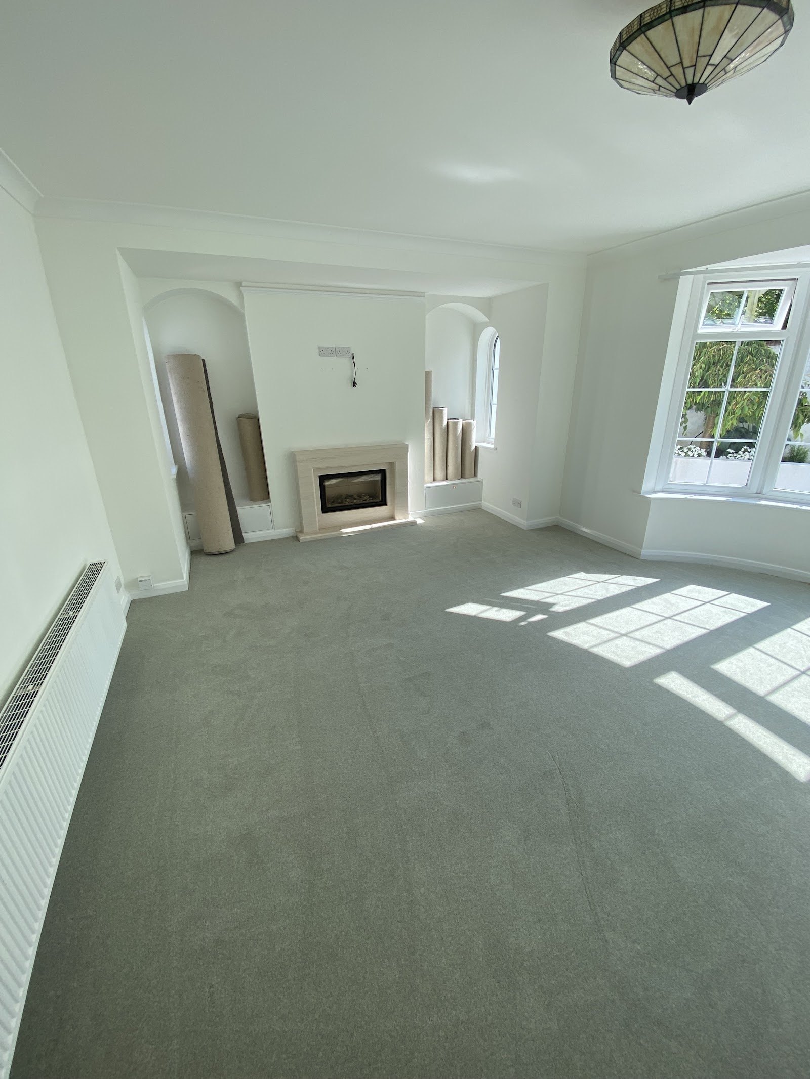 Bright living room with new grey carpet fitted to a curved bay window