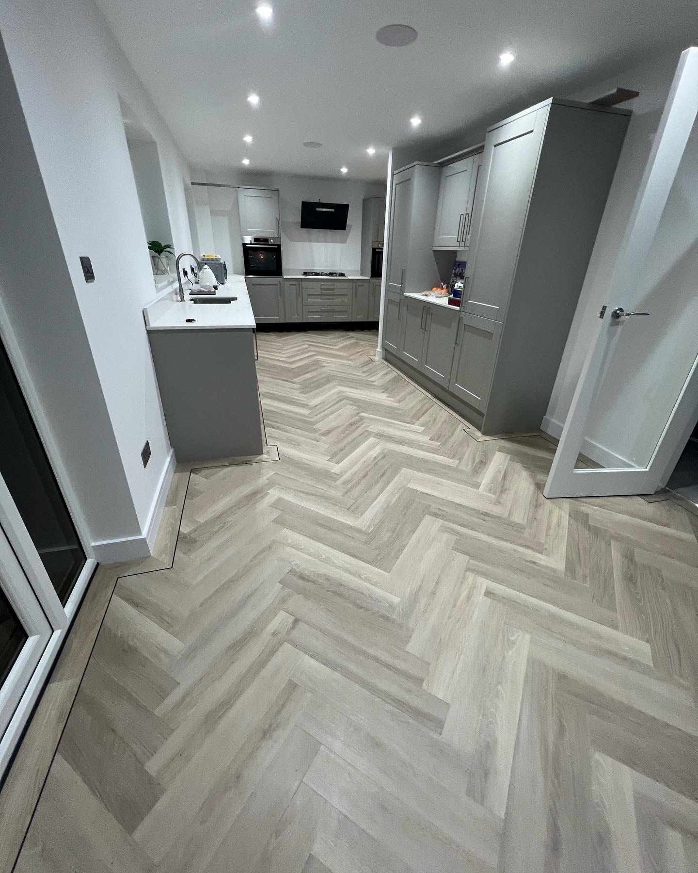 Light herringbone floor running through a modern kitchen