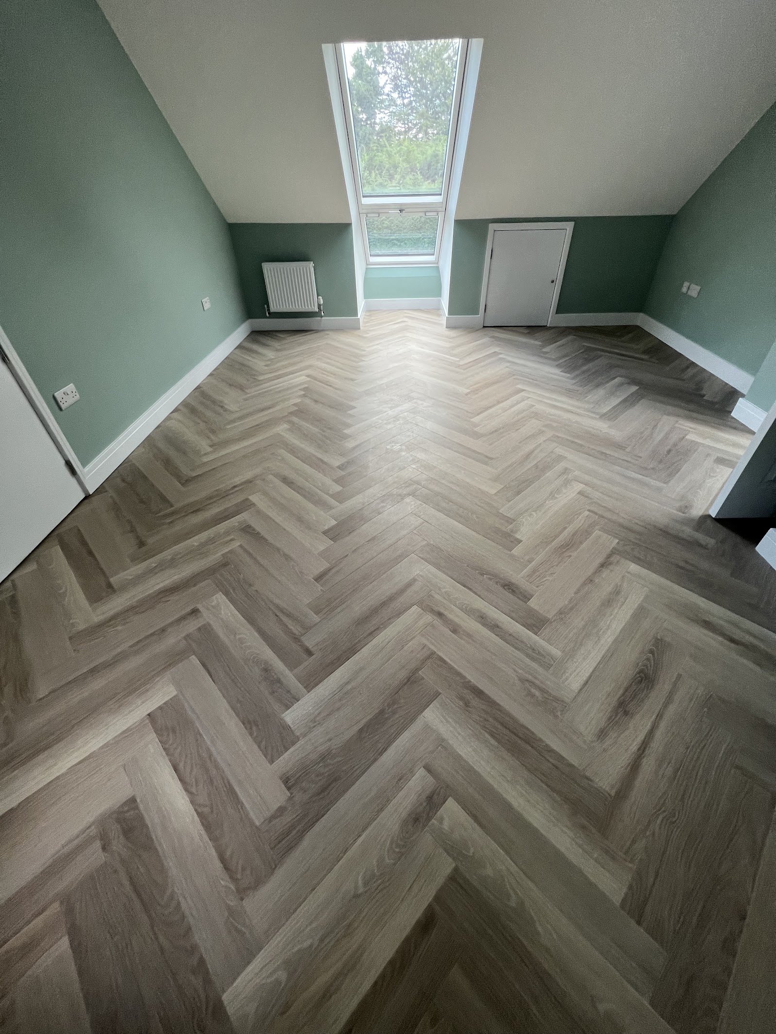 Grey herringbone floor in a green-walled room