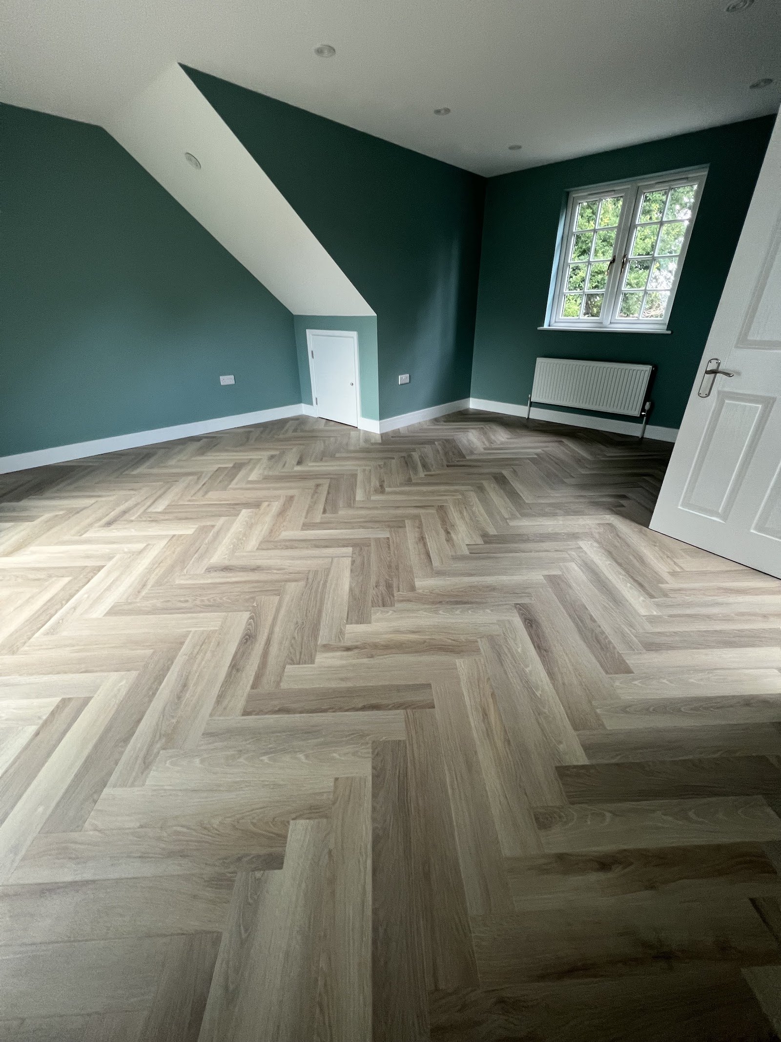 Herringbone floor in a lounge with a dark green feature wall