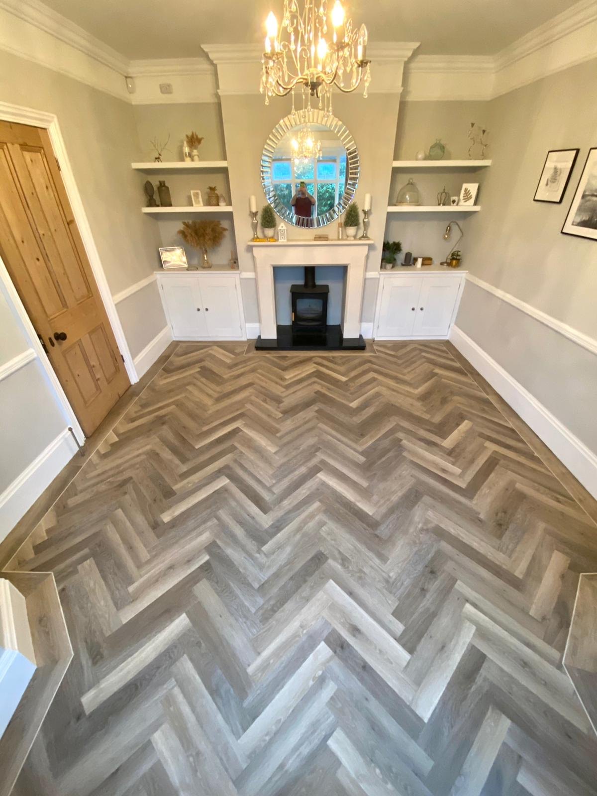 Grey oak herringbone floor in a lounge with a fireplace and shelving