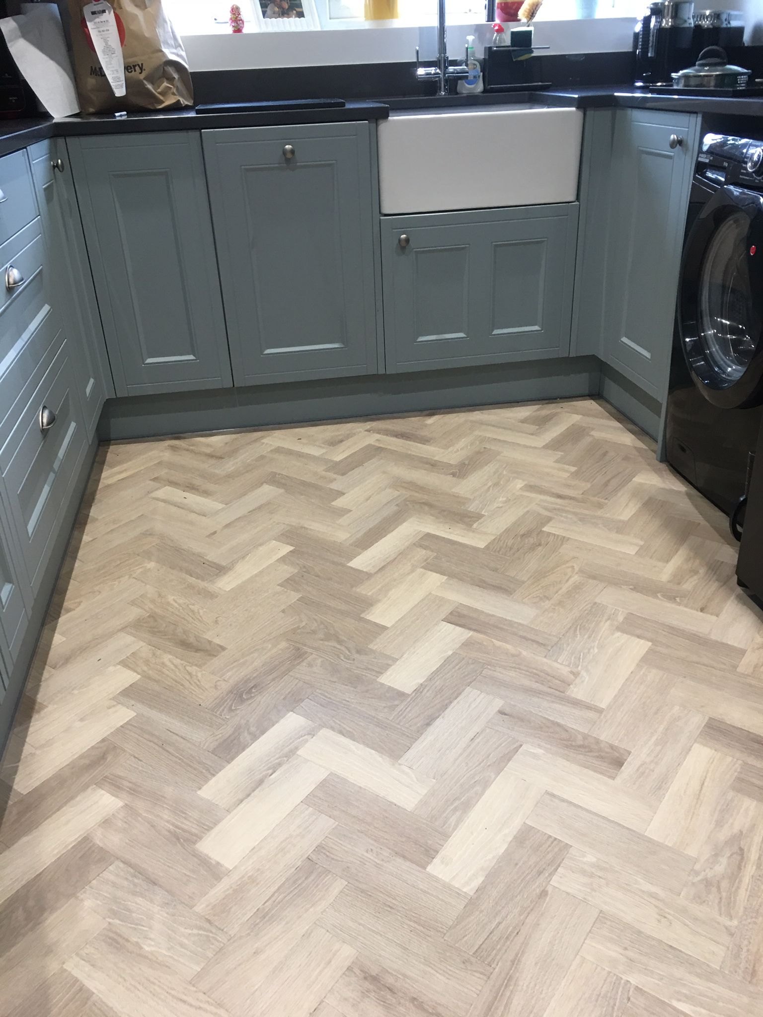 Light herringbone floor in a kitchen with grey units