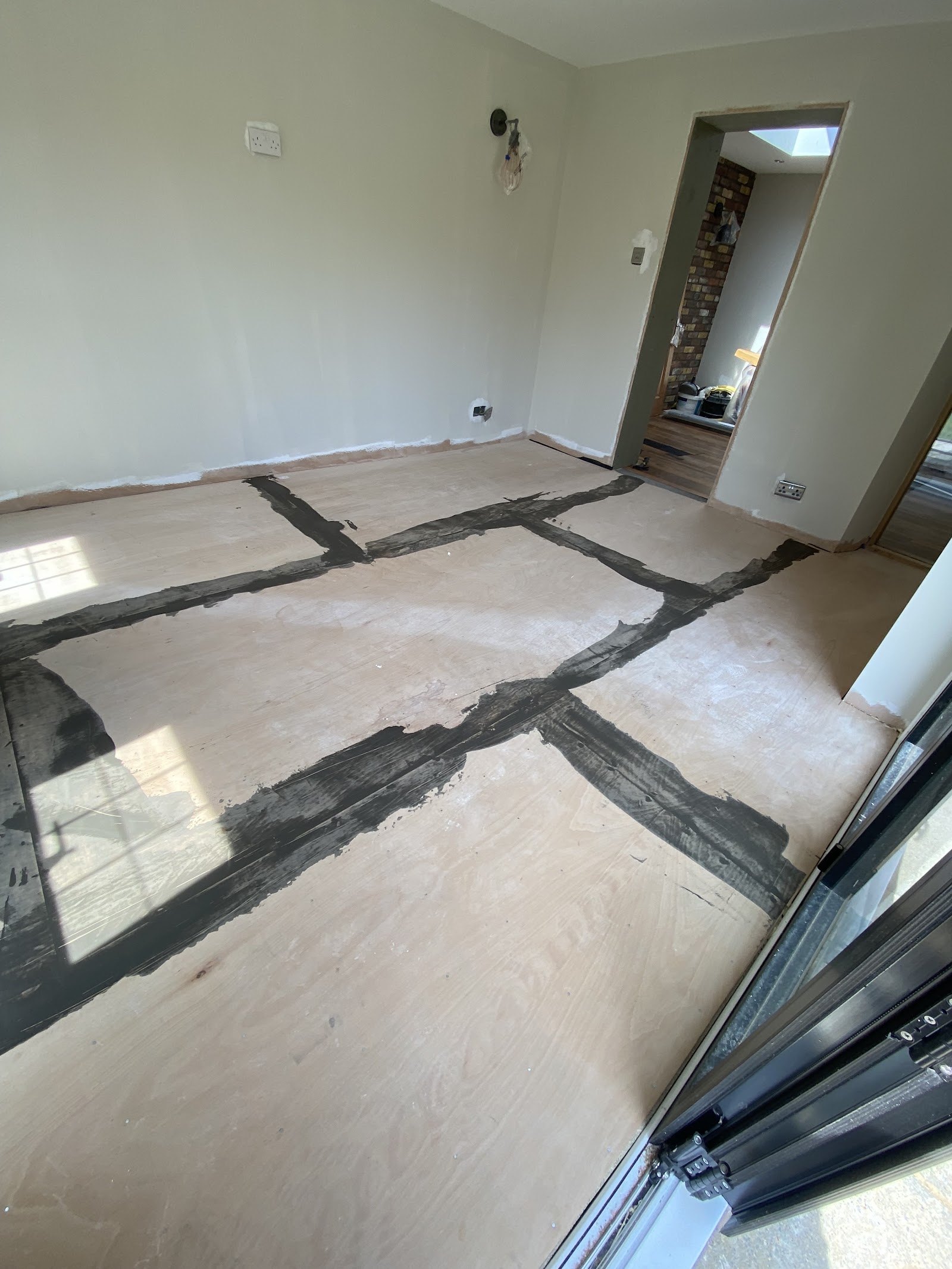 Plywood boards laid and taped across a room ready for the new floor