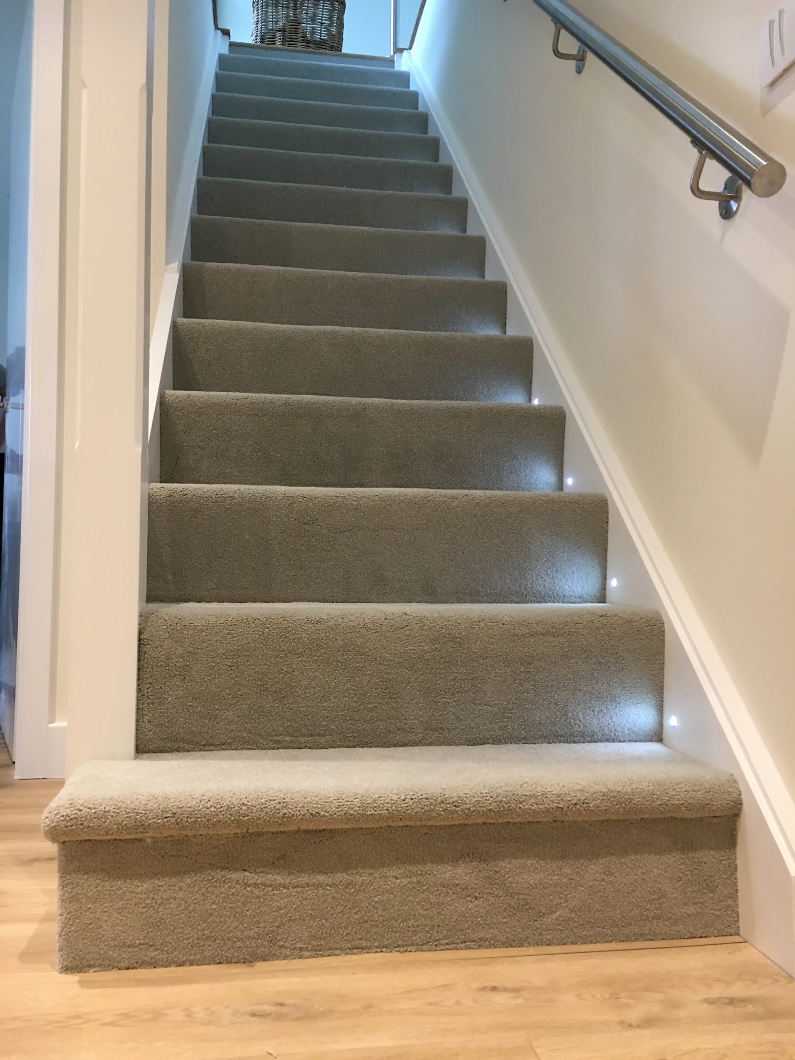 Grey carpeted staircase with step lights