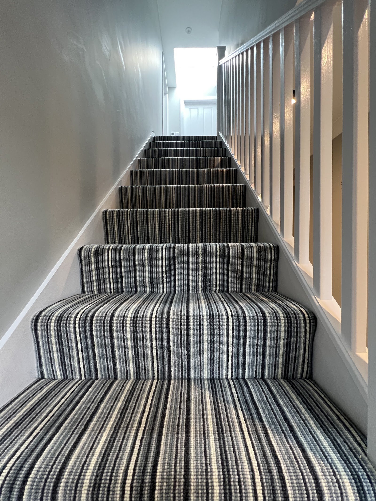Striped carpet fitted up a long straight staircase