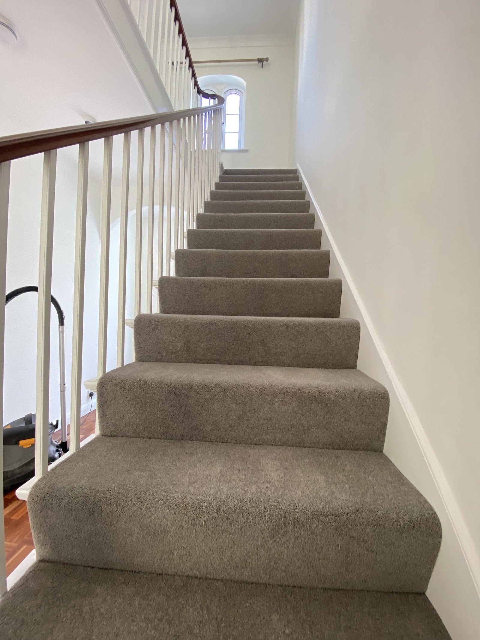 Long flight of stairs with new carpet and white spindles