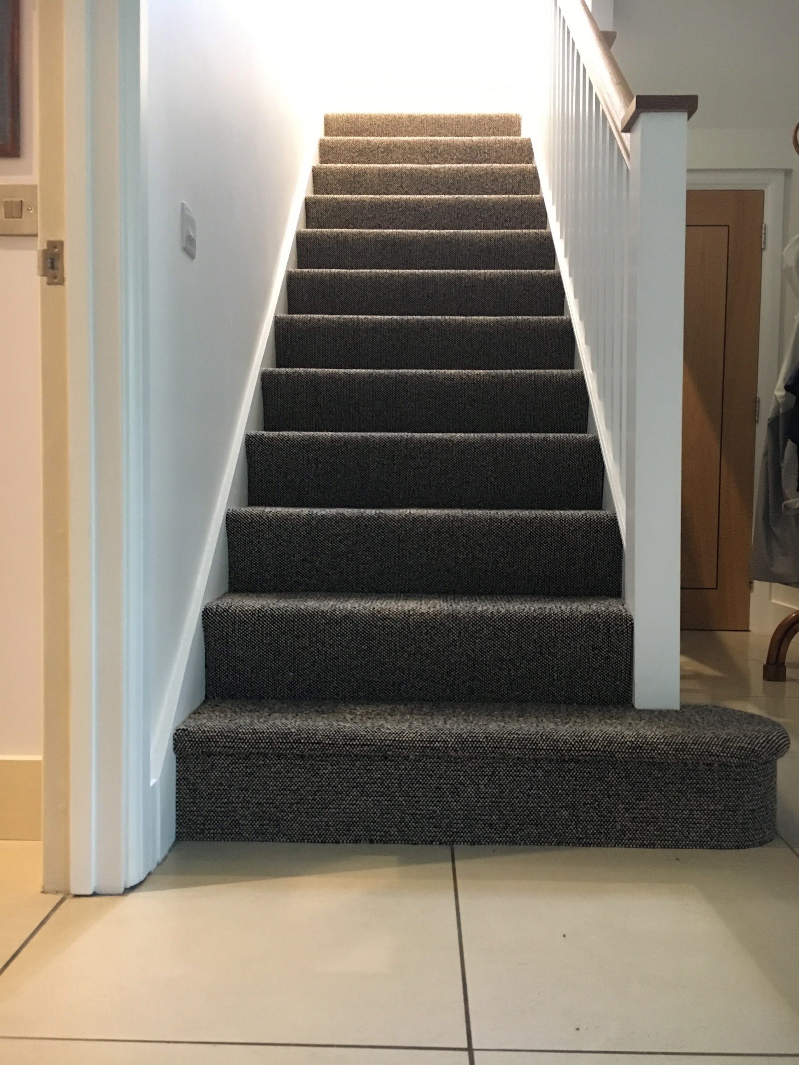 Charcoal carpet on a straight staircase above a tiled hall