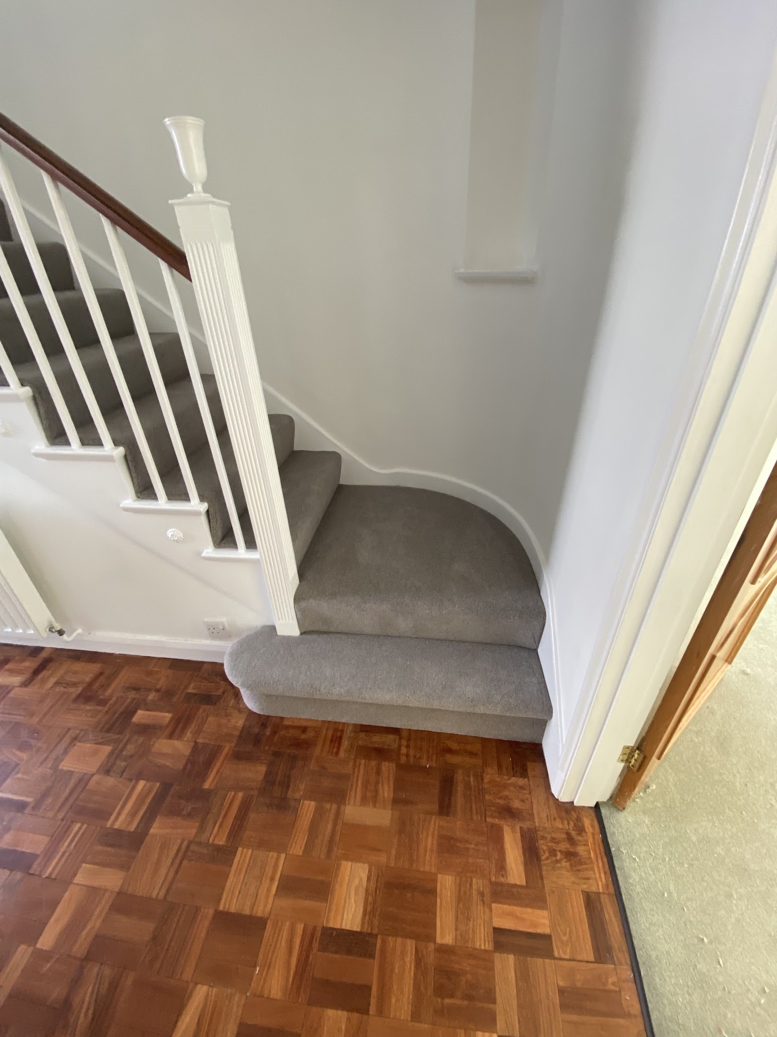 Grey carpet on a winder stair above a parquet hallway