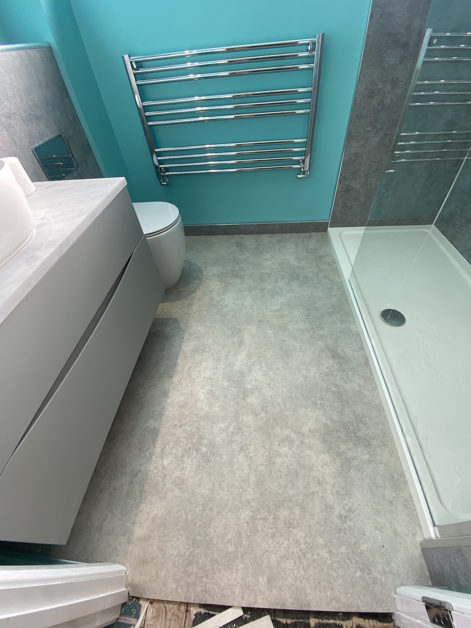 Stone-effect vinyl floor in a bright turquoise bathroom