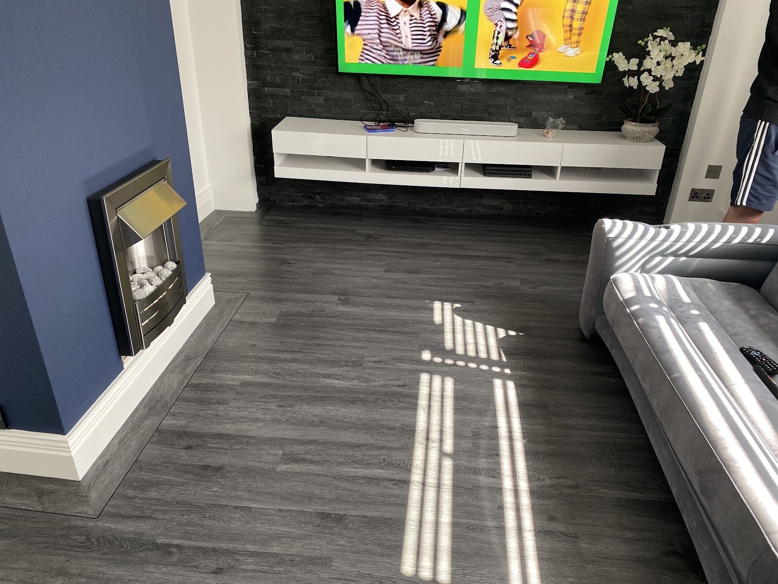 Grey wood-effect vinyl in a lounge with a navy chimney breast