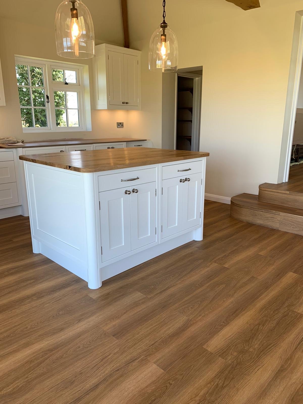 Wood-effect floor around a kitchen island under pendant lights