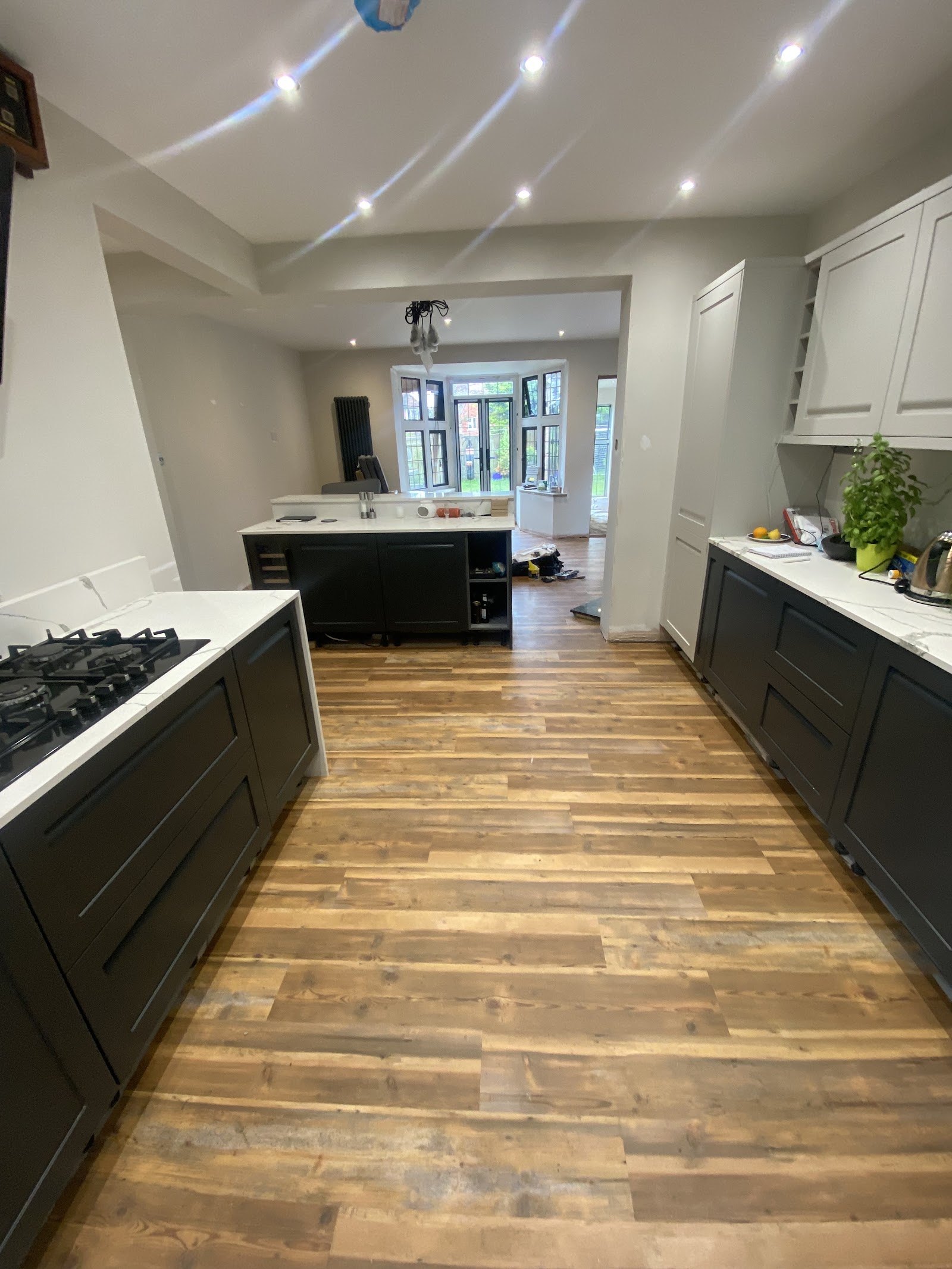 Reclaimed wood-effect floor through a kitchen with dark units